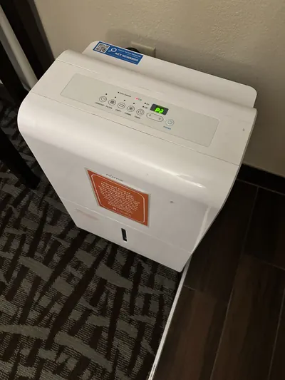 White portable dehumidifier standing on a carpeted floor